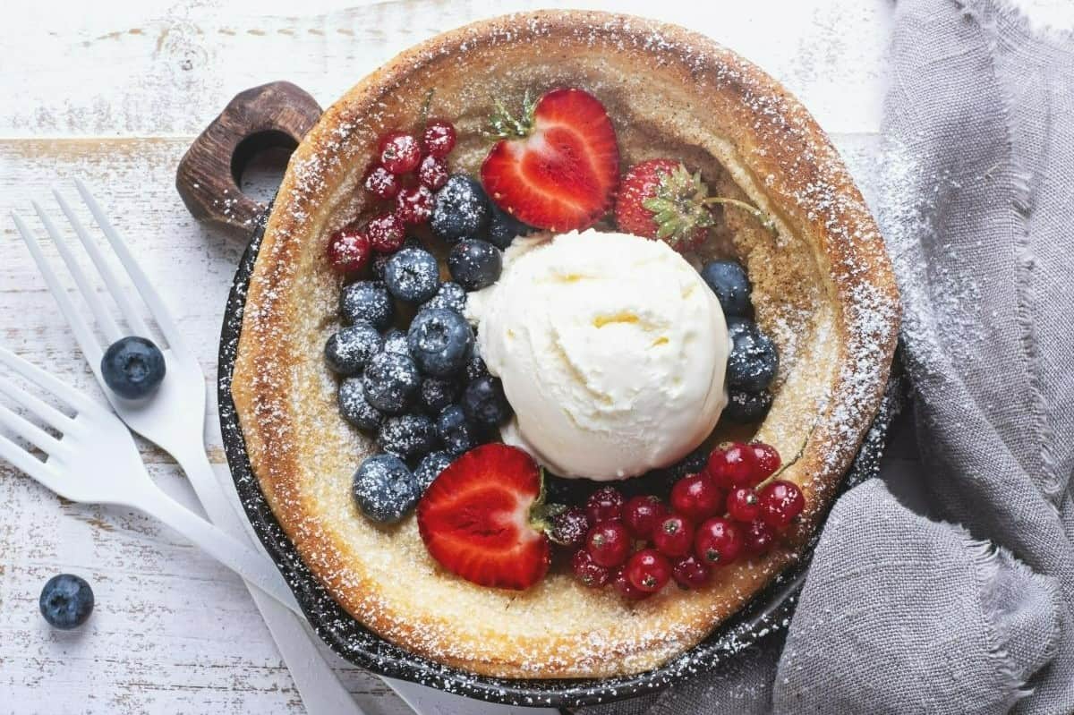 This photo shows a Yorkshire pudding filled with sweet berries and ice cream