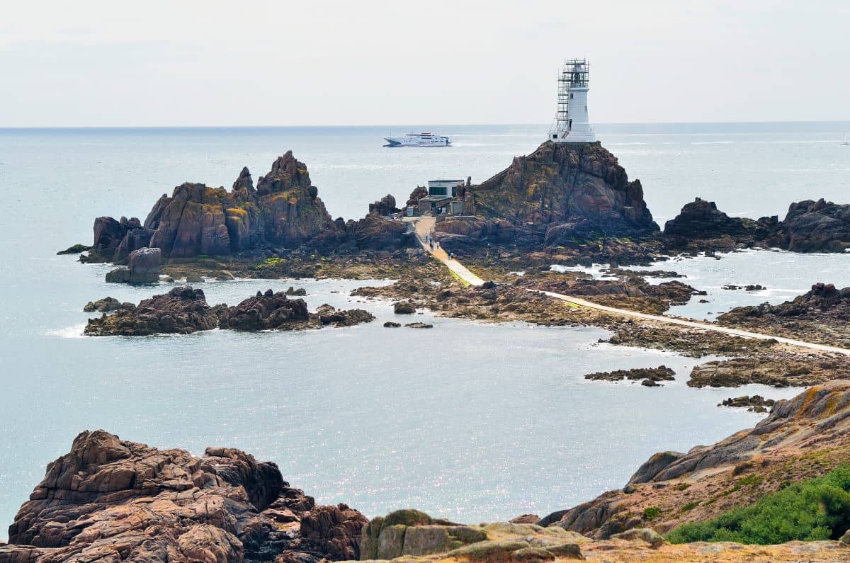 Car ferry passing La Corbiere lighthouse in Jersey, on the way to St Helier Harbour